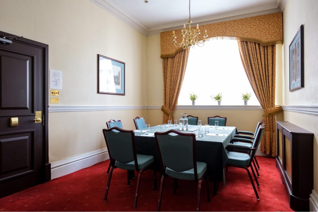 The Minster Room arranged for a small meeting beside a large window.
